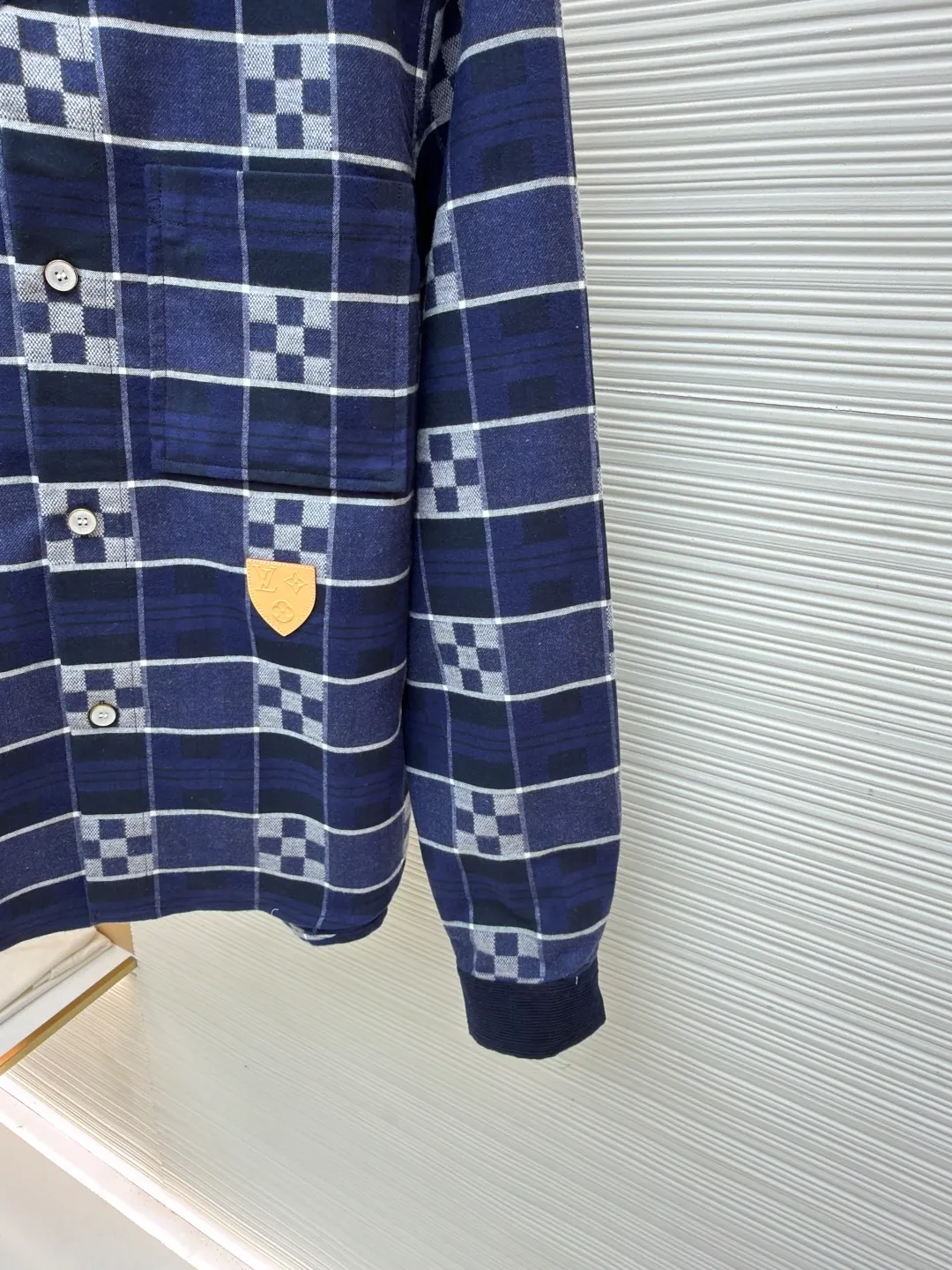 LOUIS VUITTON SKI ski series flannel checkerboard long-sleeved shirt ●Original version: purchased and developed by 14289 ●Item number: 1682075-B50 ●Fabric: flannel fabric ●Technology: printing production ●Color: blue ●Version: fitted version ●Weight: about 725 grams ●Size: S-M-L-XL ●Description: The checkered texture of dark and light navy blue and gray is woven through the yarn-dyed weaving process, in which the brand's classic Damier checkerboard element is embedded. The texture is clear and the color fastness is excellent. The body is spliced ​​with corduroy lapels and cuffs, the velvet strips are fine and full, and the high-temperature shaping process ensures stiffness. The placket uses natural mother-of-pearl buttons, which are hand-polished and polished to give it a warm texture; the leather plaque at the hem is made of first-layer calfskin, which is embossed and hot stamped to present the brand logo, and the edges are hand-oiled to be smooth and burr-free. The overall tailoring is shaped by three-dimensional cutting technology to create a fitted silhouette. The stitching line adopts double-needle overlocking technology, and every inch of stitches is evenly arranged. The embedded shoulder and side seams make the clothes more comfortable to wear. The exquisite clothing craftsmanship and brand ingenuity are fully demonstrated in the details.